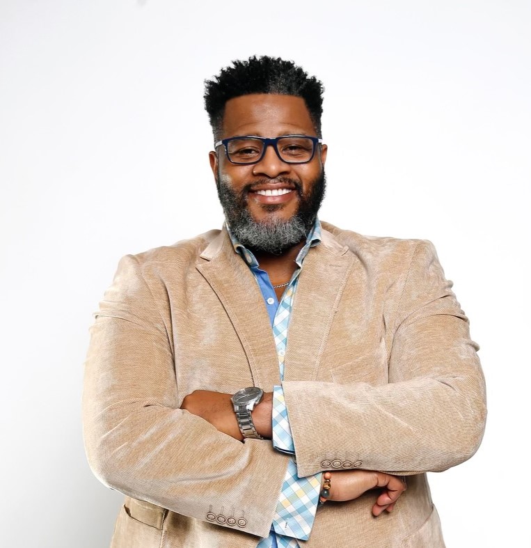 Dr. Derrick Traylor smiling in a tan jacket